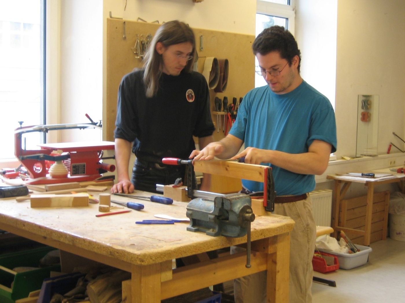 Ein Zivildiener und ein Klient in einer Werkstätte bei der Herstellung eines Werkstückes aus Holz
